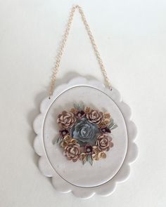 a white plate with flowers on it hanging from a chain