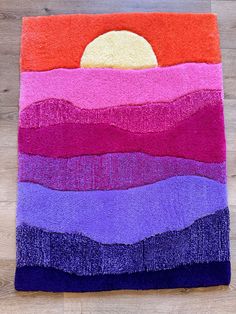 a multicolored rug on the floor with a sun in the sky above it