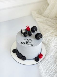 a white birthday cake with black and red wheels on the top is sitting on a table