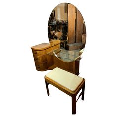 a mirror sitting on top of a wooden dresser next to a stool and table with a bench underneath it