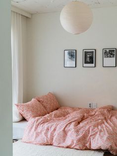 an unmade bed in a white room with three pictures on the wall above it