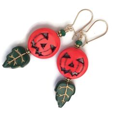 "Classic Jack O Lantern earrings for Halloween.  Carved, orange howlite pumpkins are matched with pressed-glass green leaves and crystal accents.  Petaled 22K gold plated findings fit the autumnal, botanical scene.  Spooktacular! Quality 14K gold-filled ear wires - choose from kidney or French.  14K gold-filled head pins.  Length is 2\". All my Etsy jewelry offerings are designed and created by me. As an independent craftsperson, I value your patronage. Please use coupon code 10OFF2 at checkout Jack O Lantern Earrings, Green Novelty Earrings For Halloween, Green Earrings For Halloween Gift, Handmade Green Halloween Earrings, Green Halloween Dangle Earrings, Green Novelty Jewelry For Halloween, Classic Jack O Lantern, Orange Jack O Lantern, Thanksgiving Earrings