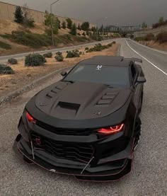 a black sports car is parked on the side of the road with its hood up