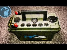 an army green toolbox with buttons and knobs on the side sitting on carpet