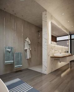 a modern bathroom with wood flooring and marble walls, along with white towels hanging on the wall