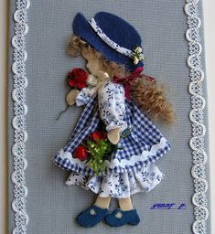 a little doll with flowers and a hat on it's head is in a frame