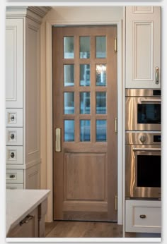 a kitchen with an oven, microwave and wooden door