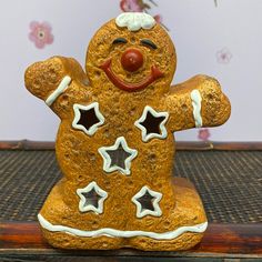 a ceramic gingerbread man with stars on his face and nose, standing on top of a wooden table