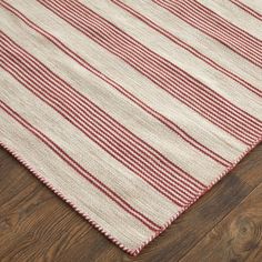 a red and white striped rug on the floor with wood floors in the background,