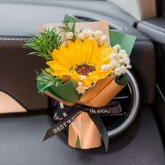 a bouquet of flowers sitting on top of a steering wheel in a car with ribbons around it