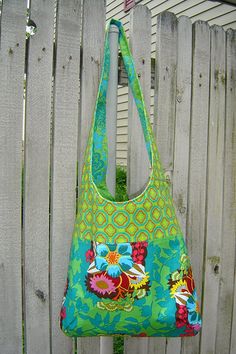 a handbag hanging on a fence with flowers in the front and side pockets open