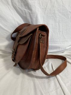 "Measurements are 13\" wide, 10\"5 high, 3\"4 deep with a 54\" shoulder strap at it's longest with a 24\"5 drop. On the interior there is one main compartment with 2 back zipper pocket, two back pockets, lined in twill fabric and a front pocket under flap closure. Leather is lightly oil waxed with brass tone hardware and one exterior pocket for easy access. The leather is strong with no tears and bag can be used crossbody. This bag is great for work,school and daily use. ------------------------ Leather Saddle Flap Bag For Everyday Use, Everyday Use Saddle Flap Bag With Adjustable Strap, Leather Saddle Bag With Waxed Finish Satchel, Leather Saddle Bag With Waxed Finish, Everyday Vintage Brown Satchel With Leather Lining, Brown Saddle Bag With Leather Lining And Flap, Leather Lined Saddle Flap Bag, Brown Leather Saddle Bag With Flap And Leather Lining, Classic Saddle Bag With Waxed Finish For Everyday Use