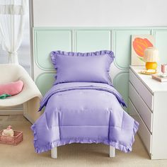 a purple bed in a bedroom next to a white dresser and chair with a pink pillow on it