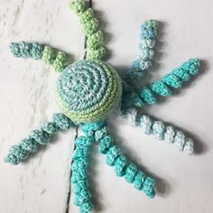 a crocheted green and blue object sitting on top of a white table