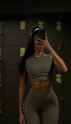 a woman in grey sports bra top and leggings taking a selfie with her cell phone