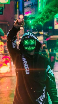 a man in a black hoodie with green neon lights on his face and hands