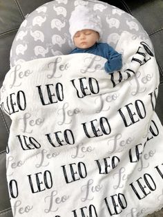 a baby wrapped up in a blanket with the words leo leo written on it