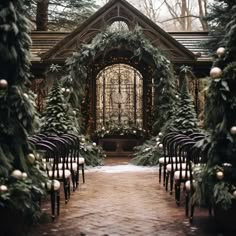 an outdoor ceremony set up with candles and greenery on the aisle, surrounded by evergreen trees