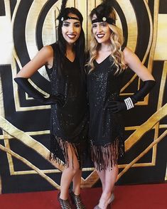 two women dressed in flappers and gats pose for a photo on the red carpet