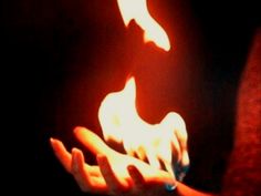 a person holding something in their hand with flames coming out of it's fingers