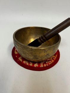 an old singing bowl with a wooden stick sticking out of it's top, on a red coaster