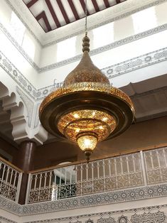 a chandelier hanging from the ceiling in a room with white walls and railings