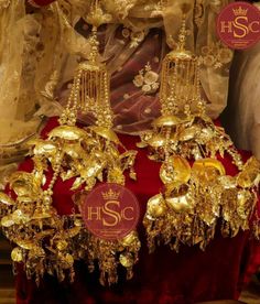 gold jewelry is displayed in front of a red velvet tablecloth and white drapes