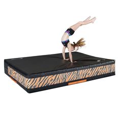 a girl is doing a handstand on an animal print mattress