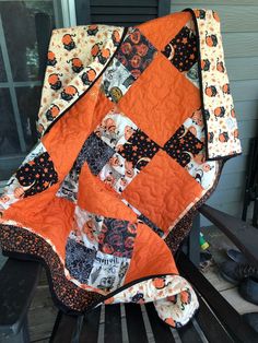 an orange and black quilt sitting on top of a wooden bench