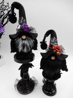 two halloween decorations are sitting on top of black candlesticks and one is wearing a witch's hat