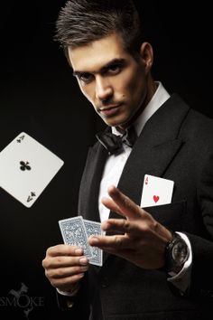 a man in a tuxedo holding playing cards