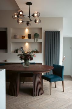 a dining room table with two chairs and a vase filled with flowers on top of it