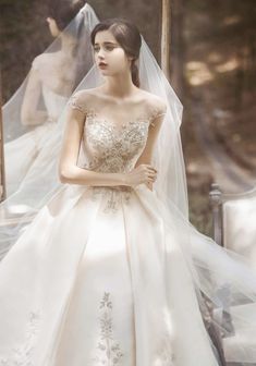 a woman wearing a wedding dress and veil in front of a window with people behind her