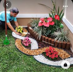 a man kneeling down next to a garden with flowers and plants in the middle of it