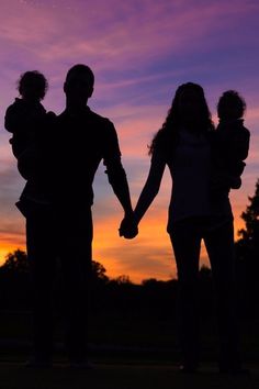 two adults and a child holding hands at sunset