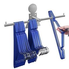 there is a hand that is holding two blue chairs on a metal rack and another person's finger is pointing at the hanger