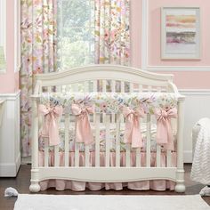 a white crib with pink and green floral curtains