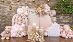 a table topped with balloons and teddy bears next to a wall covered in pink and white balloons