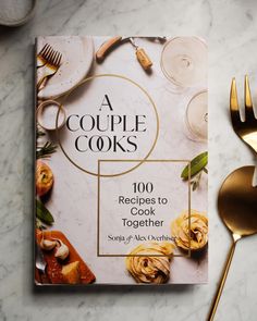 a cookbook sitting on top of a table next to gold utensils