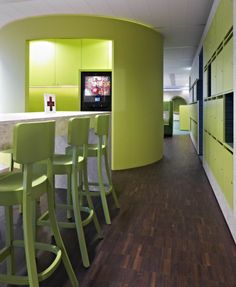 a room that has some green chairs and a tv in the wall behind two bar stools