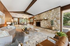 a living room with couches, chairs and a stone fireplace in the middle of it