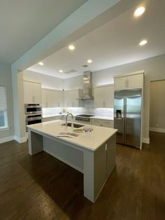 a large kitchen with an island in the middle and stainless steel appliances on both sides