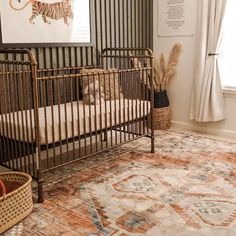 a baby crib in the corner of a room with a rug and pictures on the wall