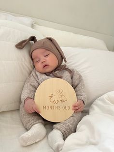 a baby is holding a wooden sign that says, months old