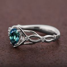 A handmade Celtic style platinum ring set with a beautiful, pear shaped Montana sapphire and small accent diamonds. The center stone is a 5mmX7mm natural Montana teal sapphire of high quality. Please note that the sapphires are natural stones and the exact shade may vary. The smaller stones are natural diamonds with a total carat weight of 0.06ct The ring is made with any of the available metals you select. All of the metals we use are 100% recycled. If you have any questions please feel free to Teardrop Emerald Ring With Diamond Prong Setting, Teardrop Diamond Ring With Accent Stones, Diamond Teardrop Emerald Ring For Promise, Teardrop Diamond Emerald Ring For Promise, Teardrop Sapphire Ring With Diamond And Prong Setting, Teardrop Sapphire Ring With Accent Stones For Formal Events, Sapphire Pear Shaped Rings For Anniversary, Formal Teardrop Sapphire Ring With Accent Stones, Pear-shaped Emerald Ring With Accent Stones For Promise