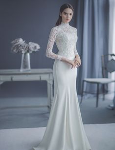 a woman in a white dress standing next to a table