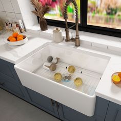 a white kitchen sink sitting under a window next to a counter top with oranges on it