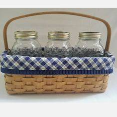 three mason jars in a basket with blue and white gingham fabric on the bottom