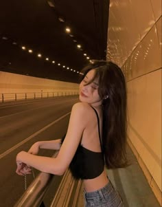 a woman leaning on a rail in an underground tunnel with her hand on the railing