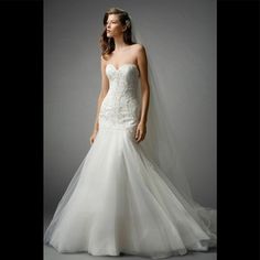 a woman in a white wedding dress with a veil on her head is standing against a gray background